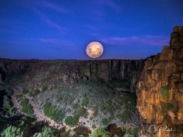 The moon in the night sky above the canyon at Tiger Canyon Private Game Reserve